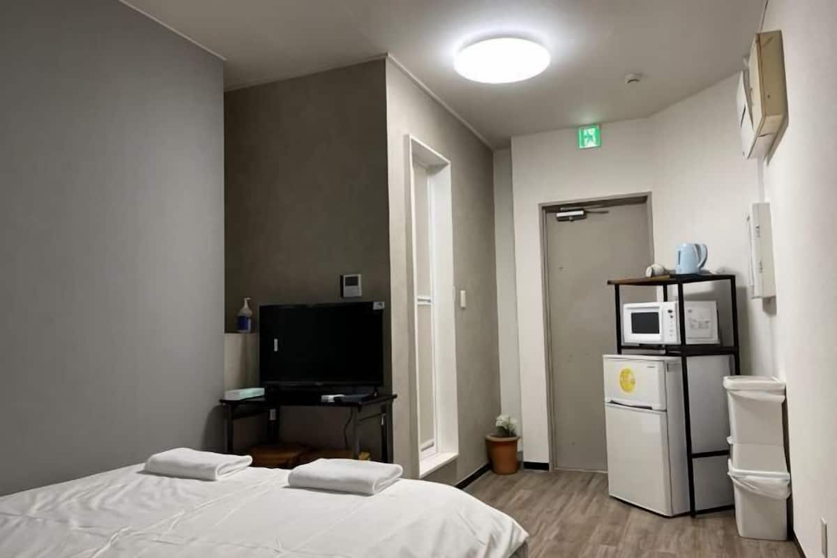 Ein Hotelzimmer mit einem Bett, einem Schreibtisch, einem Fernseher, einer Mikrowelle und einem Papierkorb.