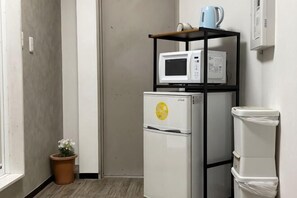 A compact kitchenette with a refrigerator, microwave, and a small shelf with a kettle. - Tokyo guest (Tokyo)
