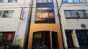 A multi-story building with a central entrance, a bicycle parked in front, and a sign on the left. - Tokyo guest (Tokyo)