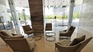A modern lobby with a central seating area, glass partitions, and a view of the outside. - C2011 Almas Suites Studio Netflix Johor by STAY (Iskandar Puteri)
