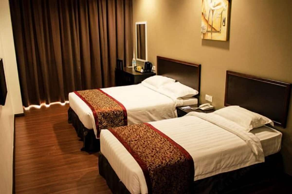 Une chambre d’hôtel avec deux lits, une table de chevet avec une lampe, un miroir et un tableau au mur.