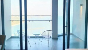 A balcony with a view of the sea, featuring two white chairs and a small table. - A La Carte Ha Long Apartments by Kevin & Anna (Ha Long)
