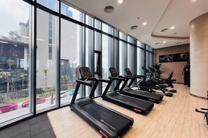 A gym with treadmills and exercise equipment, large windows, and a view of the outside. - A La Carte Ha Long Bay Apartments by Kevin & Anna (Ha Long)