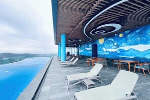 Un espace piscine aménagé sur le toit, avec des chaises longues et une fresque murale.