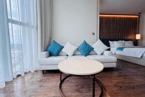 Une chambre d’hôtel moderne avec un canapé, une table basse ronde et un lit doté d’une tête de lit.