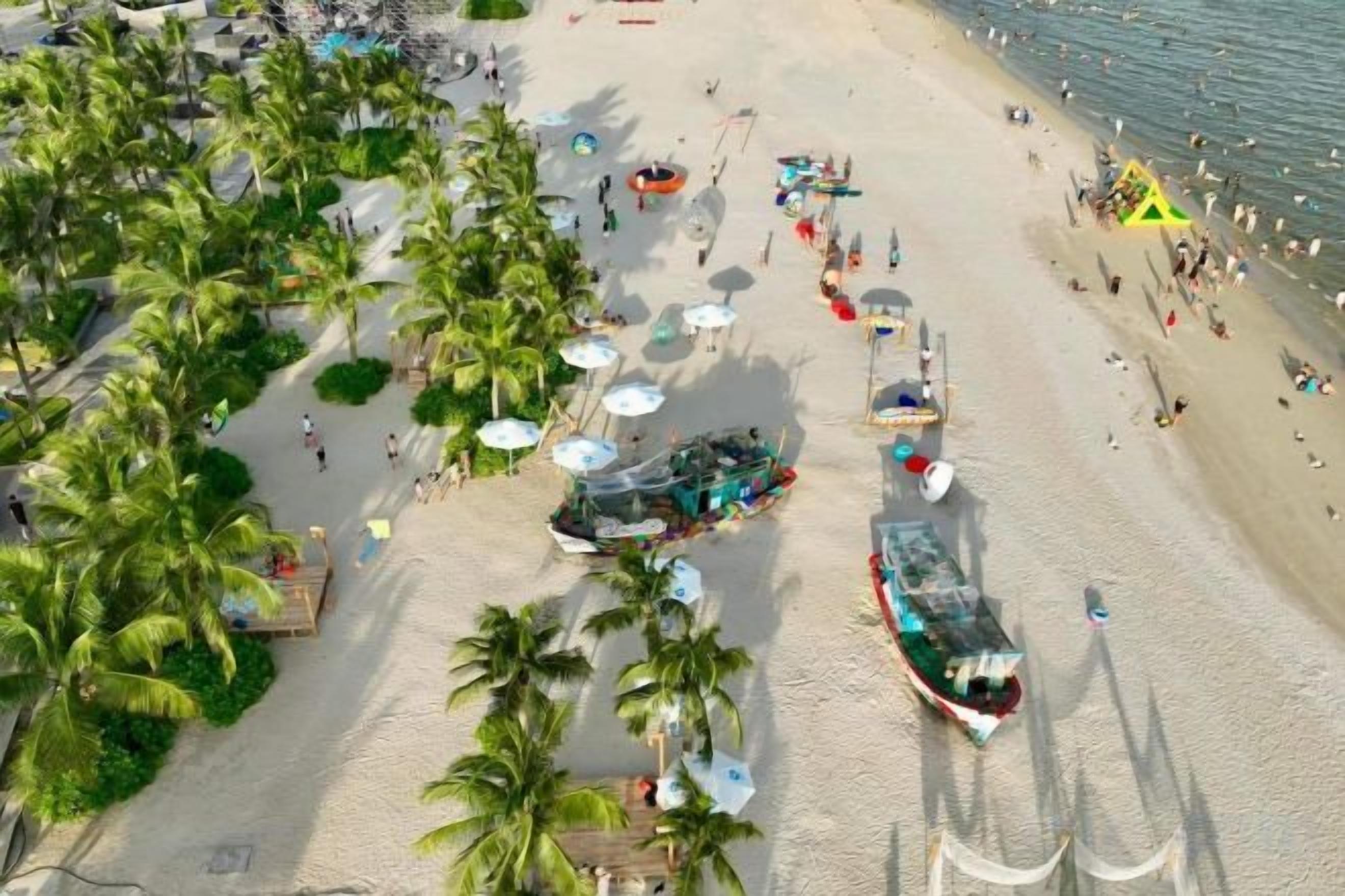 A beach with palm trees, umbrellas, and people.