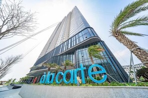 A modern high-rise building with a prominent glass facade and a sign that reads 'alcarte.' - A La Carte Ha Long Bay Apartments by Kevin & Anna (Ha Long)
