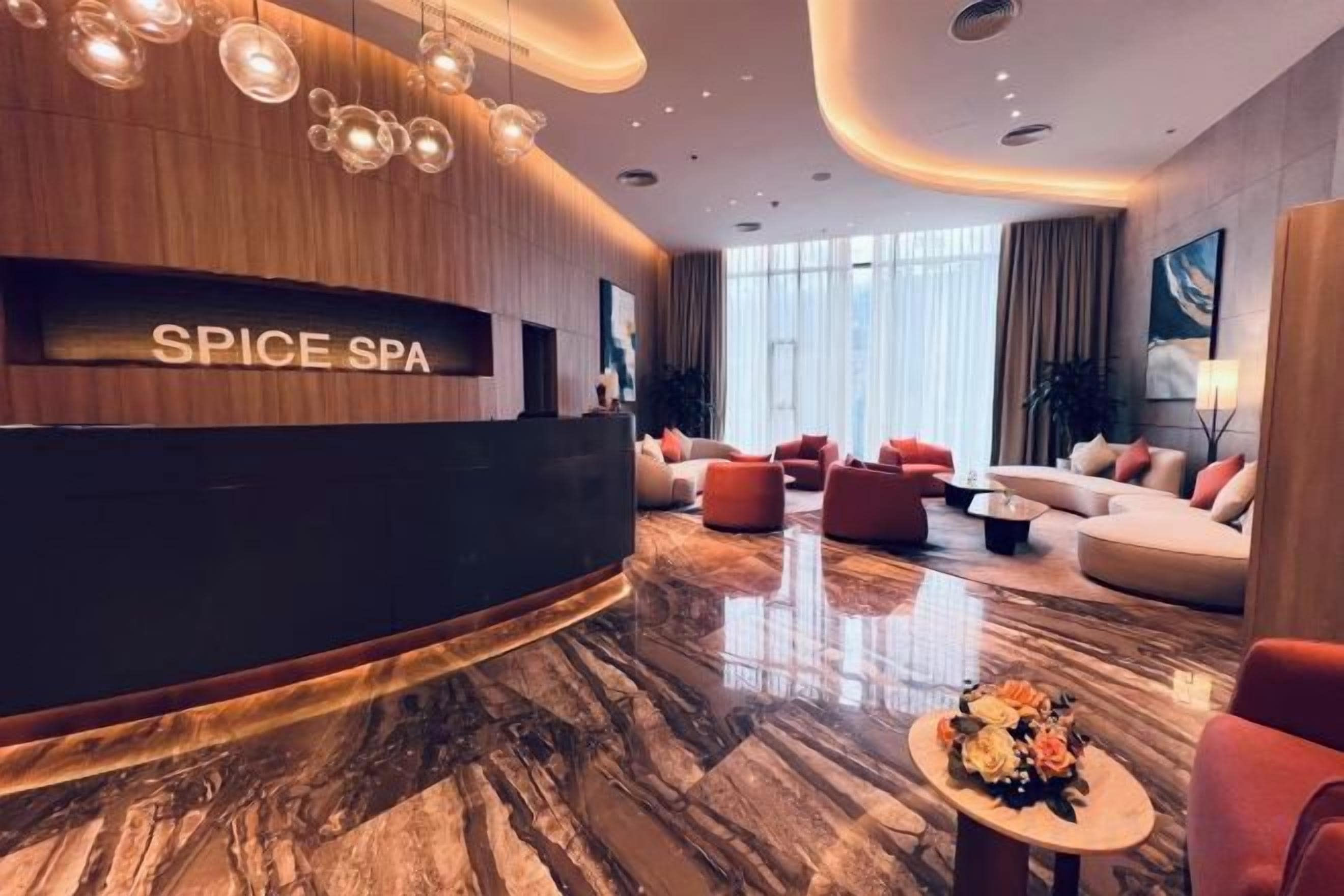 Un moderno vestíbulo de spa con mostrador de recepción, asientos mullidos y suelo de mármol.