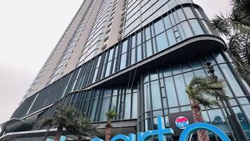 Un immeuble de grande hauteur à la façade incurvée, bordé de palmiers, et sur lequel on peut lire l’inscription « hôtel ».