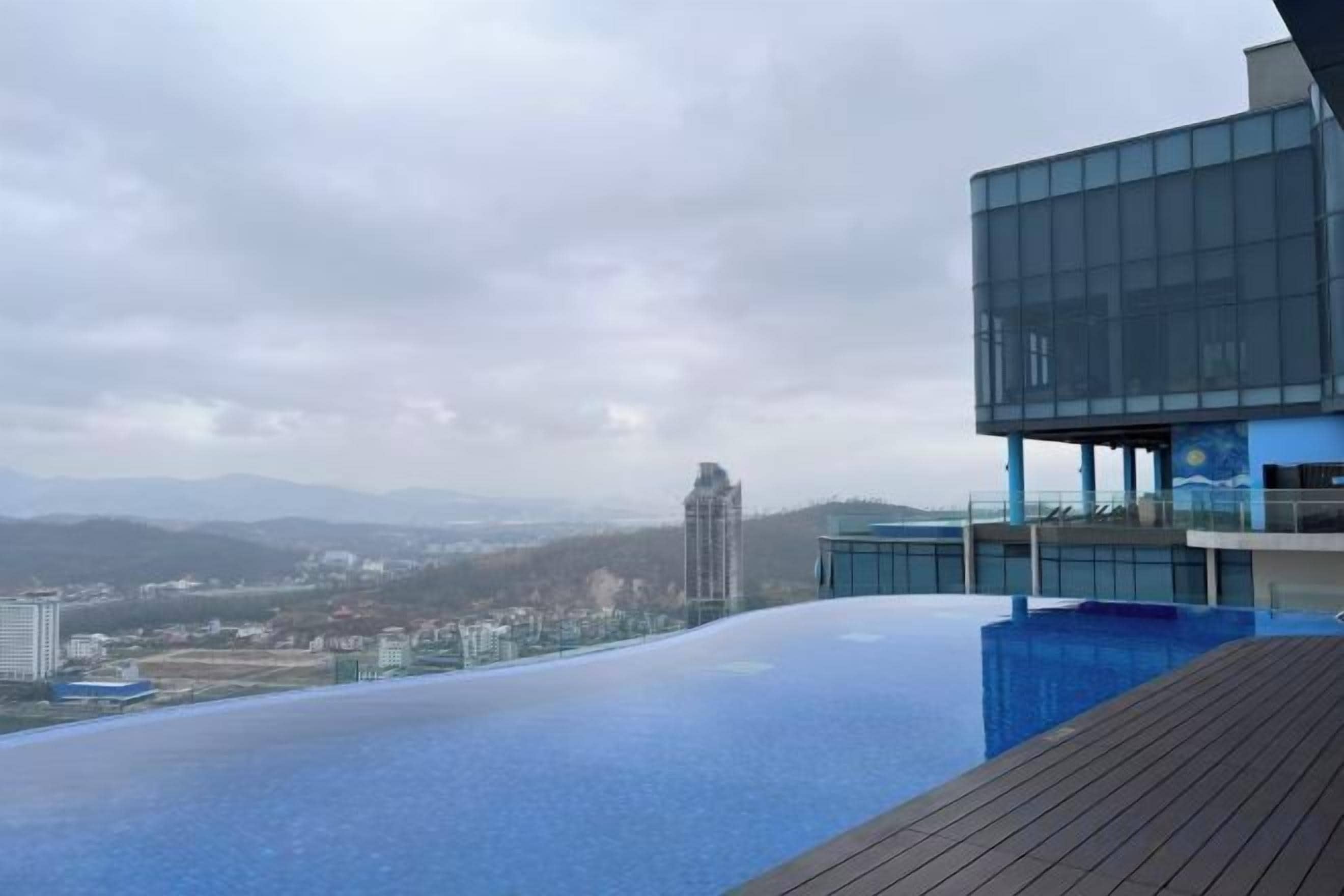 A modern building with a rooftop pool overlooking a cityscape.