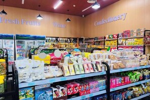 L’intérieur d’une épicerie, avec des rayons étiquetés « Fruits frais », « Vins » et « Confiseries ».