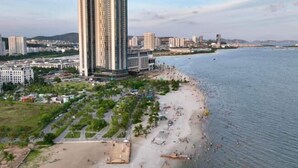 A coastal cityscape with a prominent high-rise hotel, a sandy beach, and a marina. - A La Carte Ha Long Apartments by Kevin & Anna (Ha Long)
