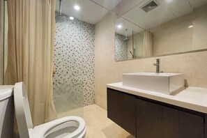 Un baño moderno con inodoro, lavamanos y zona de ducha.