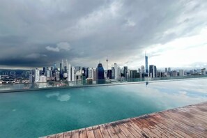 Un horizonte urbano reflejado en aguas tranquilas, con una cubierta de madera al frente.