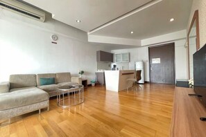 Una sala moderna con sofá, mesa de centro y una cocina con refrigerador y microondas.