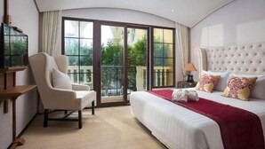Ein Hotelzimmer mit einem großen Bett, einem Sessel, einem Fernseher und einem Balkon mit Blick.
