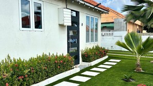 A modern building with a red-tiled roof, white walls, and a well-maintained lawn with stepping stones.