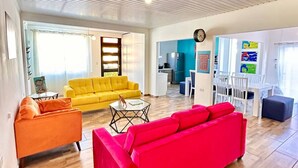 A spacious living area with a wooden floor, a bright yellow sofa, a red sofa, and a small coffee table.
