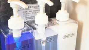 Tre flaconi di sapone liquido con erogatori a pompa, uno etichettato 'SHAMPOO' e l'altro 'SAPONE CORPO'.