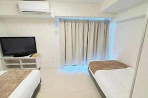 A hotel room with two beds, a TV, and an air conditioning unit. - Rakuyado Sanno (Osaka)