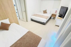 A hotel room with a bed, a desk, a television, and a door leading to another room. - Rakuyado Sanno (Osaka)