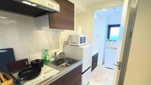 Una cucina compatta con forno a microonde, lavello e piccolo frigorifero.