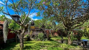 A garden with various plants and a statue. - Raja Asri Guest House Sanur Mitra RedDoorz (Bali)