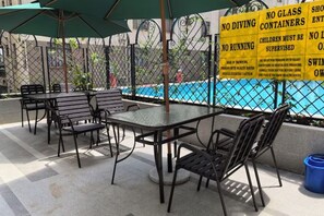 An outdoor seating area with tables and chairs, a pool, and a safety sign. - Nairobi Xiaomi Hotel (Nairobi)