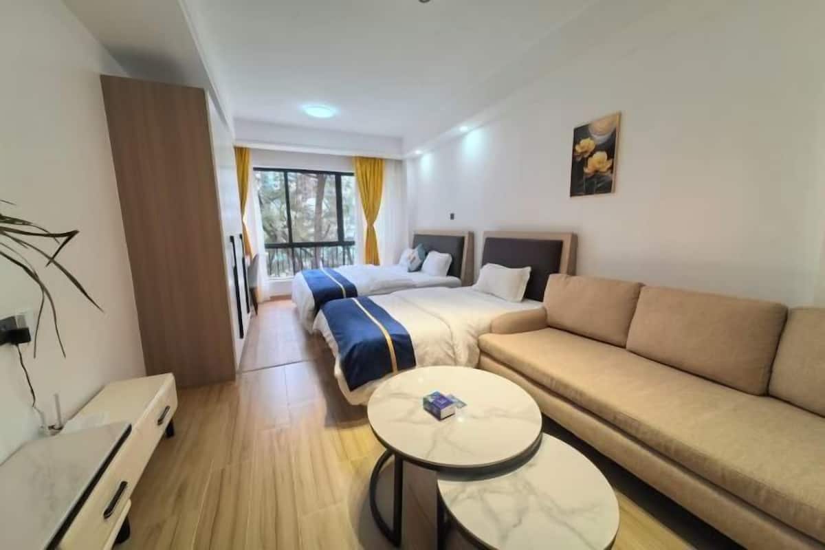 A hotel room with a bed, a sofa, a round table, and a window with curtains.