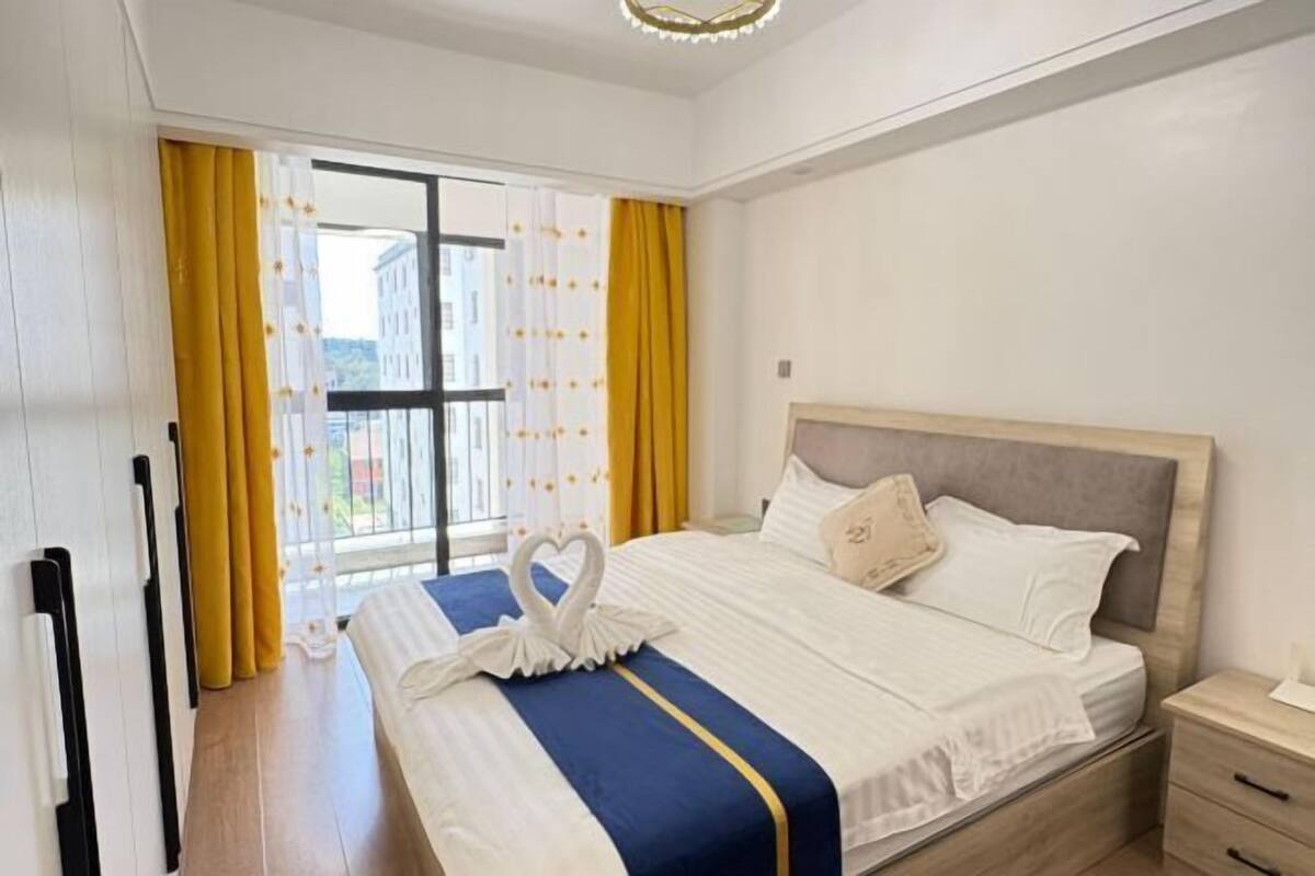 A hotel room with a bed, a nightstand, and a window with curtains.