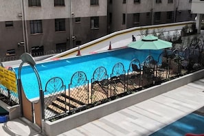 A swimming pool with a metal fence, a slide, and a few lounge chairs. - Nairobi Xiaomi Hotel (Nairobi)