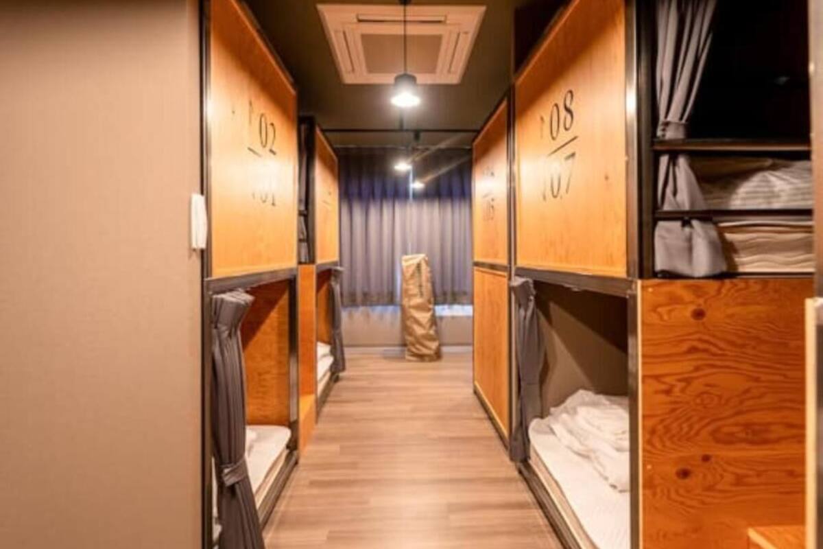 A corridor with bunk beds, wooden walls, and a curtain at the end.