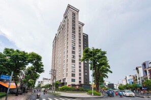 Un grand immeuble d’habitation à plusieurs étages, entouré d’arbres et situé près d’un passage pour piétons.