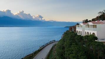 A coastal hotel with a view of the sea and mountains in the background.
