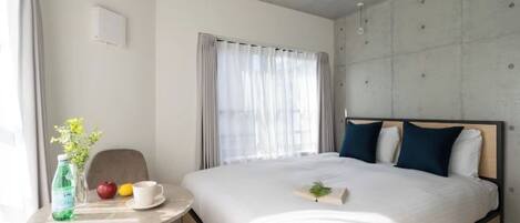 Habitación de hotel con una cama, una mesita con una botella, una manzana y una taza.