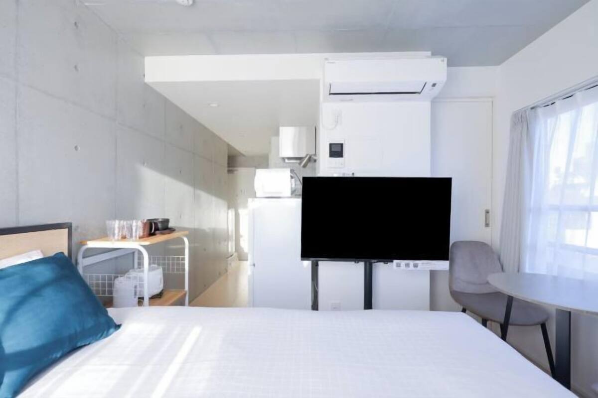 A hotel room with a bed, a TV, a small table, and a chair.