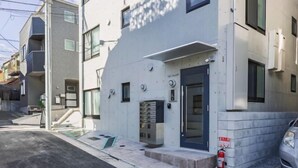 A modern building with a flat facade, a fire extinguisher, and a parked car. - Bel Avenir (Tokyo)