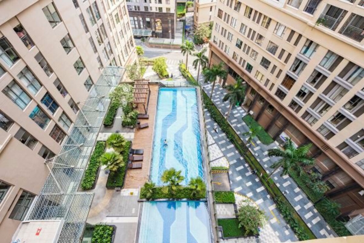 A residential building with a swimming pool, balconies, and greenery.