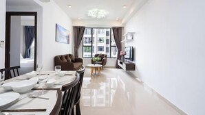 A modern living room with a dining area, large windows, and a flat-screen TV. - Saigon Royal and Tresor apartments (Ho Chi Minh City)