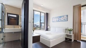 A modern hotel room with a large bed, a bathroom with a glass shower enclosure, and a city view. - Saigon Royal and Tresor apartments (Ho Chi Minh City)