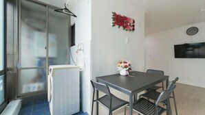 Una habitación con una mesa, sillas, un radiador, un reloj y una ventana con vistas.