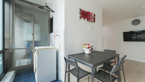A room with a table, chairs, a radiator, a clock, and a window with a view. - Seoul Yapee guesthouse /Hongik University Sta. .Big House.party room.Two Rooms. (Seoul)