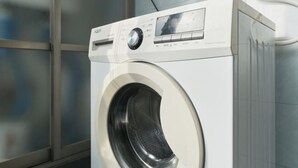 Una lavadora de carga frontal con pantalla digital, panel de control y puerta transparente.