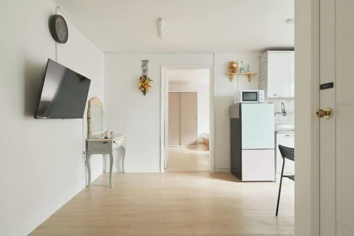 Eine moderne Küche mit Mikrowelle, Kühlschrank und einer kleinen Essecke mit einem Stuhl.