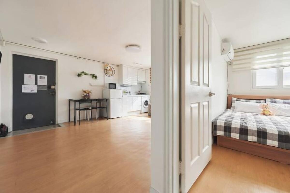 Ein kleines Zimmer mit Bett, Schreibtisch und einer Küchenzeile.
