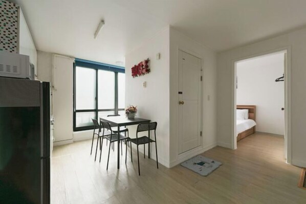 A compact living space with a dining area, a bed, and a kitchenette.
