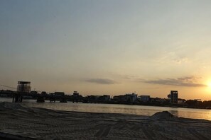 A sunset over a body of water with buildings in the background. - Suorsdei Sawadee (Kampot)