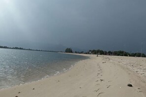 A beach with a clear sky, calm sea, and distant trees. - Suorsdei Sawadee (Kampot)