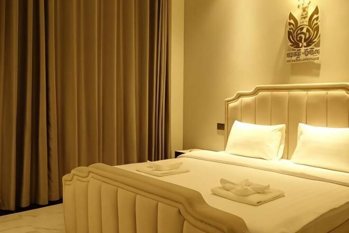 A hotel room with a bed, curtains, and a wall-mounted emblem.