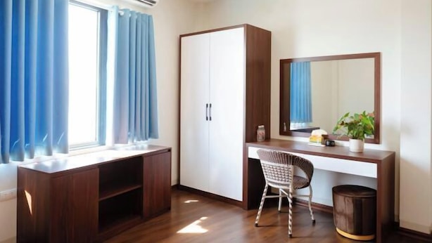A room with a desk, chair, wardrobe, mirror, and window with curtains. - NoiBaiAirportChinaHotel (Hanoi)